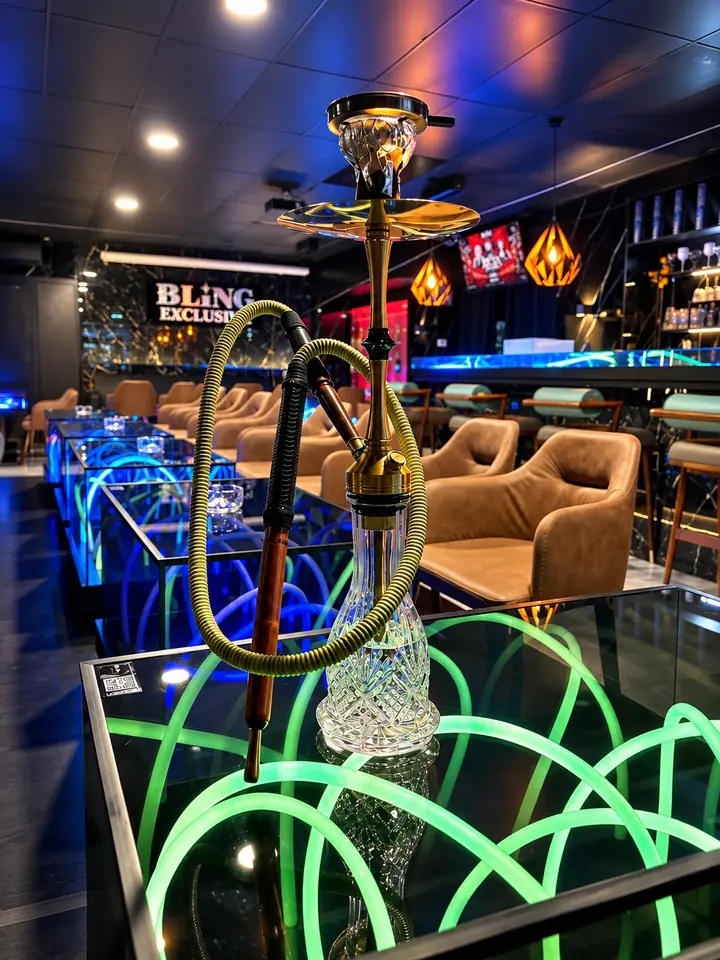 Goldene Elmas-Shisha mit Kristall-Bowl auf einem grün leuchtenden Neon-Tisch der Lounge