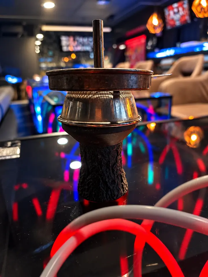 Shisha-Kopf mit Aufsatz vor rot leuchtenden Neonbögen